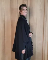 Ruana tejida de algodón con diseño abierto, terminaciones con volados y textura acanalada en los bordes.