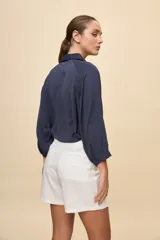 Camisa negra de calce relajado, con mangas 3/4, cuello clásico y cierre frontal con botones. Presenta detalles calados en la parte superior.