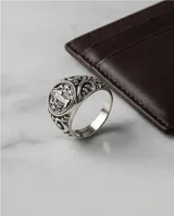 Anillo de plata con acabado empavonado, presenta un diseño circular grabado con la imagen de la Virgen Milagrosa y detalles ornamentales en los laterales.