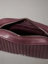 Cartera bandolera Calvin Klein color borgoña con diseño acolchado vertical. Tiene correa de cadena plateada, cierre superior con cremallera y logo metálico en el frente.