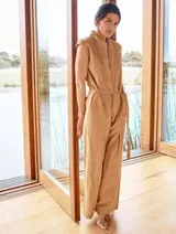 Mono color arena de lino, con cuello mao, cierre frontal con cremallera, mangas cortas y cinturón de lazo.