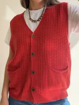 Chaleco de tejido de punto con textura, escote en V y cierre frontal con botones. Presenta dos bolsillos delanteros y terminaciones en tejido acanalado en el ruedo.