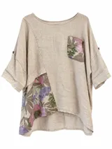 Blusa beige de lino con detalles estampados florales en un bolsillo superior y en un lateral inferior, manga corta y corte asimétrico holgado.