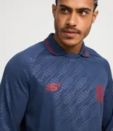 Camisa masculina con cuello polo con raya contrastante, mangas largas, puños ajustados con raya contrastante, estampas localizadas en el pecho y estampa heatprint. La prenda posee tecnologia dry.