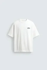 Camiseta de corte relajado, cuello redondo y manga corta. Presenta un pequeño estampado de texto en el pecho y un estampado gráfico de mayor tamaño en la espalda.