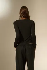 Top de manga larga color negro, con cuello en V y diseño drapeado en el frente. Confeccionado en tejido ajustado al cuerpo.