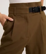 Short sastre de corte recto y cintura alta color verde militar, con pinzas delanteras, trabillas para cinturón y cierre frontal oculto. Incluye un medio cinturón lateral de poliuretano con hebilla.