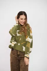 Buzo de tejido de punto con diseño estampado abstracto en tonos verde, blanco y mostaza. Presenta cuello redondo, mangas largas y un corte holgado con ruedo recto.