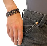 Pulsera elástica de cuentas tubulares color marrón, negro y dorado.