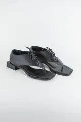 Sandalias de cuero color negro, estilo ojota con capellada acordonada, punta cuadrada y taco bloque bajo.