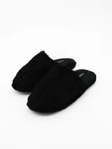 Pantuflas de estar por casa color negro, confeccionadas en tejido de pana con textura acanalada y suela plana.