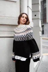 Sweater de lana con diseño de jacquard en la parte superior, cuello redondo, mangas largas y puños acanalados. Presenta un corte holgado con tajos laterales y un diseño ligeramente más corto en la parte delantera.