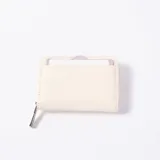 Monedero de cuero sintético texturizado color blanco, con cierre perimetral y tarjetero exterior con detalles en color lila.