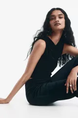 Top sin mangas de velour negro, ajustado al cuerpo, con escote cruzado drapeado y frunces laterales.