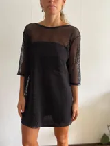 Vestido corto negro de red con mangas 3/4 y cuello redondo con ribete de cuero sintético.