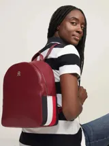 Mochila Tommy Hilfiger color rojo con detalles en azul marino. Tiene asa superior, dos correas ajustables, logo monograma metalizado de TH y cierre con cremallera.