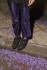 Pantalón de ecocuero color violeta metalizado, con corte capri semi oxford y tiro medio-alto. Presenta cierre frontal con botón metálico y bolsillos traseros.
