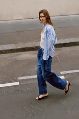 Jeans de tiro alto con corte loose fit y pernera holgada. Presenta detalle de corchetes en la cintura, bolsillos frontales y bolsillos de plastrón en la parte trasera. Cierre frontal con cremallera y botón.