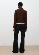 Chaqueta estructurada de tweed en color marrón, de corte recto con cuello redondo, manga larga y cierre frontal de botones. Presenta terminaciones deshilachadas y bolsillos frontales.
