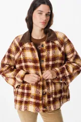 Chaqueta de corte holgado con estampado de cuadros en tonos beige, marrón y amarillo. Presenta cuello camisero en pana marrón, cierre frontal con botones y mangas largas con puños abotonados.