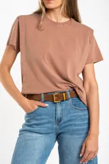 Remera de algodón color mostaza/naranja quemado, con cuello redondo y mangas cortas. Presenta un diseño con costuras externas visibles en los hombros y laterales, dándole un aspecto desestructurado.