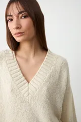 Sweater de tejido de punto color crudo, con escote en V y cuello acanalado, de diseño holgado y mangas largas.