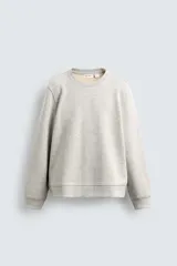 Sudadera de cuello redondo y manga larga, confeccionada en tejido de algodón pesado con interior de rizo ligeramente afelpado. Presenta un corte relajado y acabados en rib en puños y ruedo.
