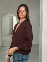Saco de punto color marrón chocolate, con escote en V, cierre frontal de botones y mangas largas con puños ajustados.