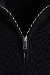 Buzo negro de tejido de punto suave, con cuello alto y medio cierre metálico. Presenta un corte estándar y manga larga con puños y bajo rectos.