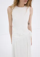 Vestido midi color blanco con diseño evasé, cuello redondo y sin mangas de tirante ancho. Cuenta con un detalle de pañuelo bordado en la cintura con cierre de cremallera lateral.
