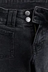 Jeans de denim negro con leve stretch, tiro bajo, corte ajustado hasta el muslo y acampanado desde la rodilla. Presenta cierre con botones en pretina prolongada y bolsillos delanteros y traseros.