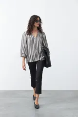 Camisa de manga larga con estampado de rayas verticales en tonos verde militar, blanco y azul marino. Presenta cuello en V y cierre frontal con botones.