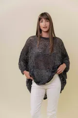 Buzo de tejido liviano y calado con brillo sutil, color gris oscuro o negro. Presenta un calce amplio y mangas amplias, con un detalle de tiras entrelazadas en la espalda. El largo es irregular, más largo en la parte trasera.