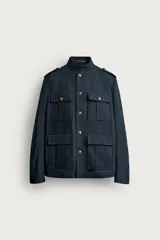 Chaqueta estilo militar relaxed fit de color azul marino, confeccionada en mezcla de algodón y lino. Presenta cuello subido, manga larga con puño abotonado, hombros con trabillas y cuatro bolsillos delanteros de parche con solapa. Se cierra al frente con botonadura metálica dorada.