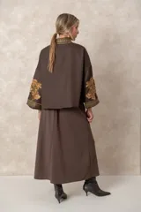 Chaqueta corta estilo kimono color chocolate, con bordados florales en tono dorado en el frente y las mangas. Presenta guardas decorativas bordadas a lo largo del cuello, la apertura frontal y los puños.