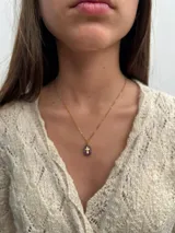 Collar con cadena dorada y dije de piedra natural pulida con cruz dorada incrustada. Disponible en tres colores: rosa, lila y blanco.