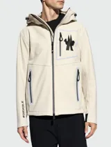 Chaqueta con capucha Moncler modelo Cormet color beige con cierre frontal con cremallera, bolsillos laterales con cremallera y logo de la marca en el pecho.