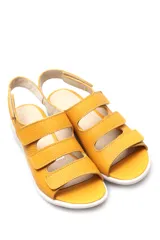 Sandalias amarillas de cuero con tres tiras con cierre de velcro y suela blanca.