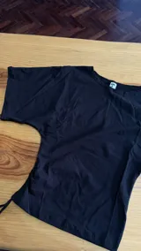 Remera manga corta básica color negro, confeccionada en algodón 100%, con diseño ajustado en la parte de la cintura y frunce regulable en el lateral derecho.