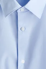 Camisa celeste de corte slim fit, con cuello inglés y cierre frontal de botones.