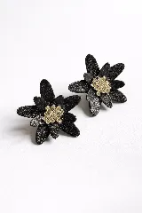 Par de aros con forma de flor, de color negro con textura brillante y centro dorado con incrustaciones de cristales.