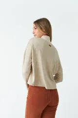 Cardigan de tejido de punto color gris melange, con escote en V, cierre frontal con botones y bolsillos tipo cartera. Presenta un diseño de corte recto y mangas largas.