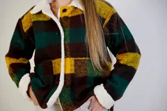 Chaqueta a cuadros color marrón, verde y amarillo, con cuello y puños de corderito sintético. Tiene cierre frontal con botones y bolsillos laterales.