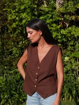 Chaleco de lino en color beige, con escote en V, cierre frontal con botones y bolsillos delanteros decorativos.