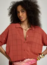 Camisa de punto de algodón color terracota con diseño a cuadros texturizados, cuello solapa, cierre frontal de botones y mangas cortas.