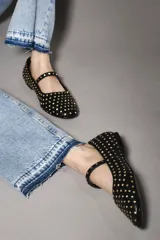 Balerinas negras con punta cuadrada, decoradas con múltiples studs dorados y una tira fina con hebilla sobre el empeine.