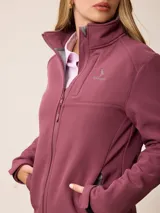Campera softshell blanca con cierre frontal completo, cuello alto y bolsillos laterales. Presenta un bolsillo vertical con cierre en el pecho y el logo de la marca bordado.