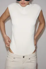 Body confeccionado en tejido elástico color crudo, con cuello redondo, manga sisa y detalle de cut out en la espalda.