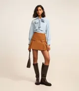 Minifalda marrón de polivelour con cierre lateral, solapas con hebillas y pliegues.