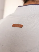 Sweater de punto en color gris claro, con cuello alto y medio cierre frontal. Presenta puños y ruedo acanalados para un ajuste cómodo.